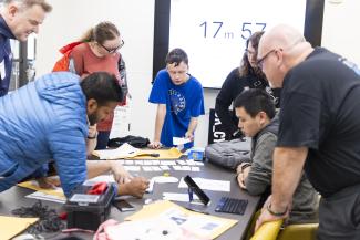 IT Policy & Privacy Analyst, Michael P. Sheron (in black T-shirt) is seen hosting a cybersecurity themed breakout game with several attendees.