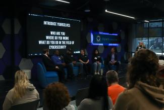 Cybersecurity careers panel with a range of guests from the FBI, CISA, & UK Cyber Team sit on the stage in the UKFCU Esport Arena.